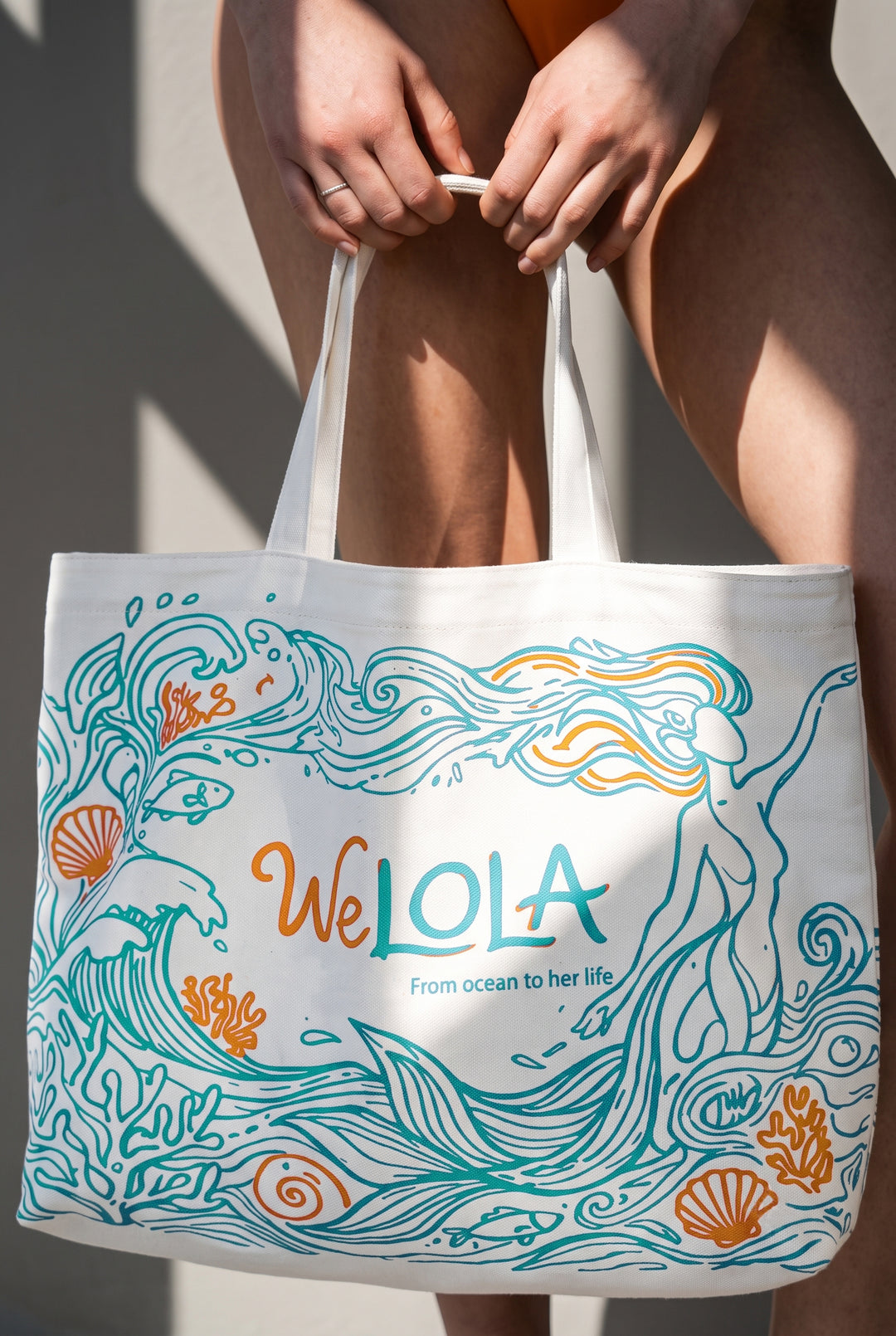 White Welola canvas beach tote bag with ocean-inspired artwork, featuring waves, seashells, coral, fish, and a coastal design.